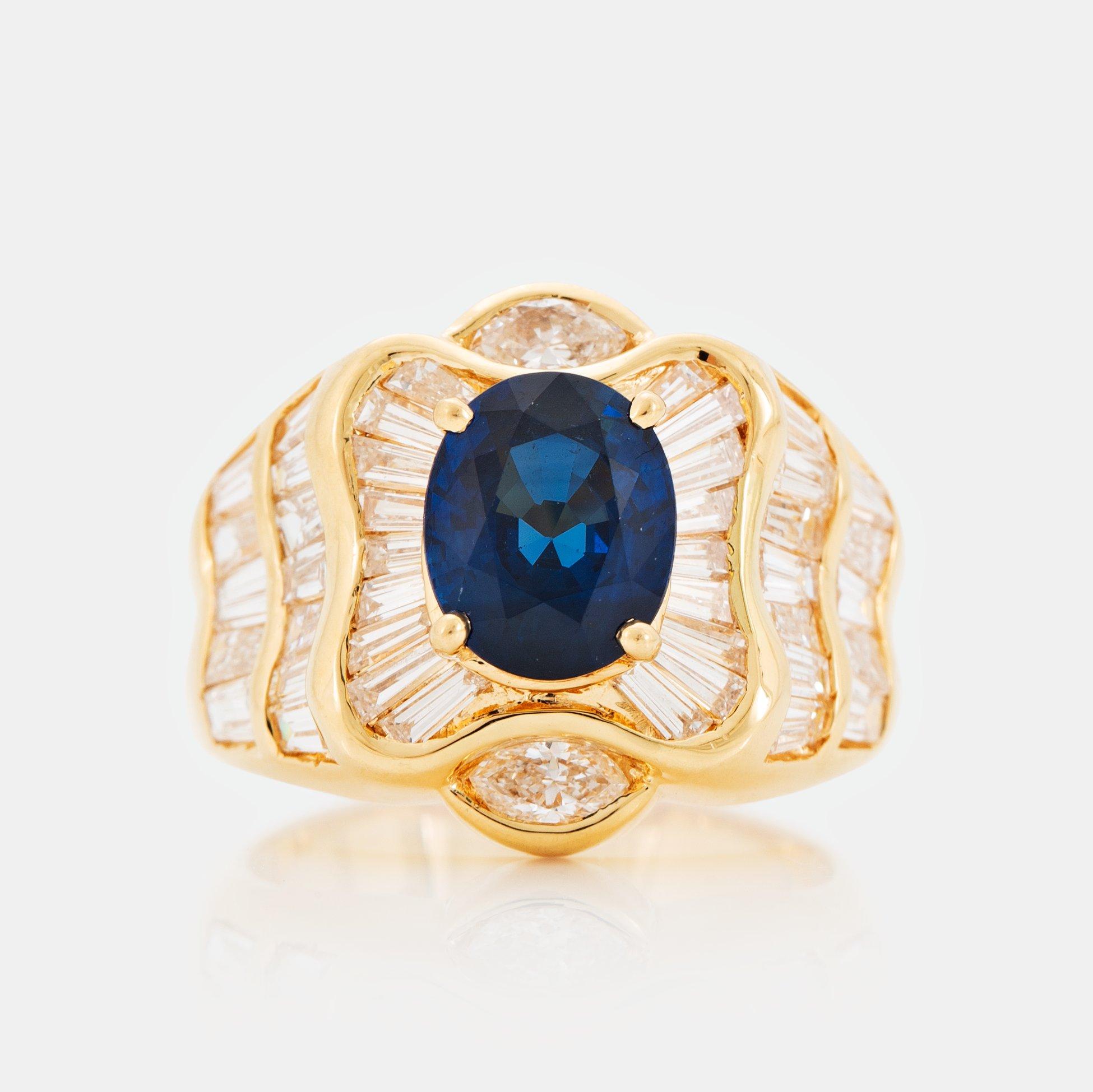 An 18K gold Junod ring set with a facted sapphire and tapered baguette-cut diamonds.