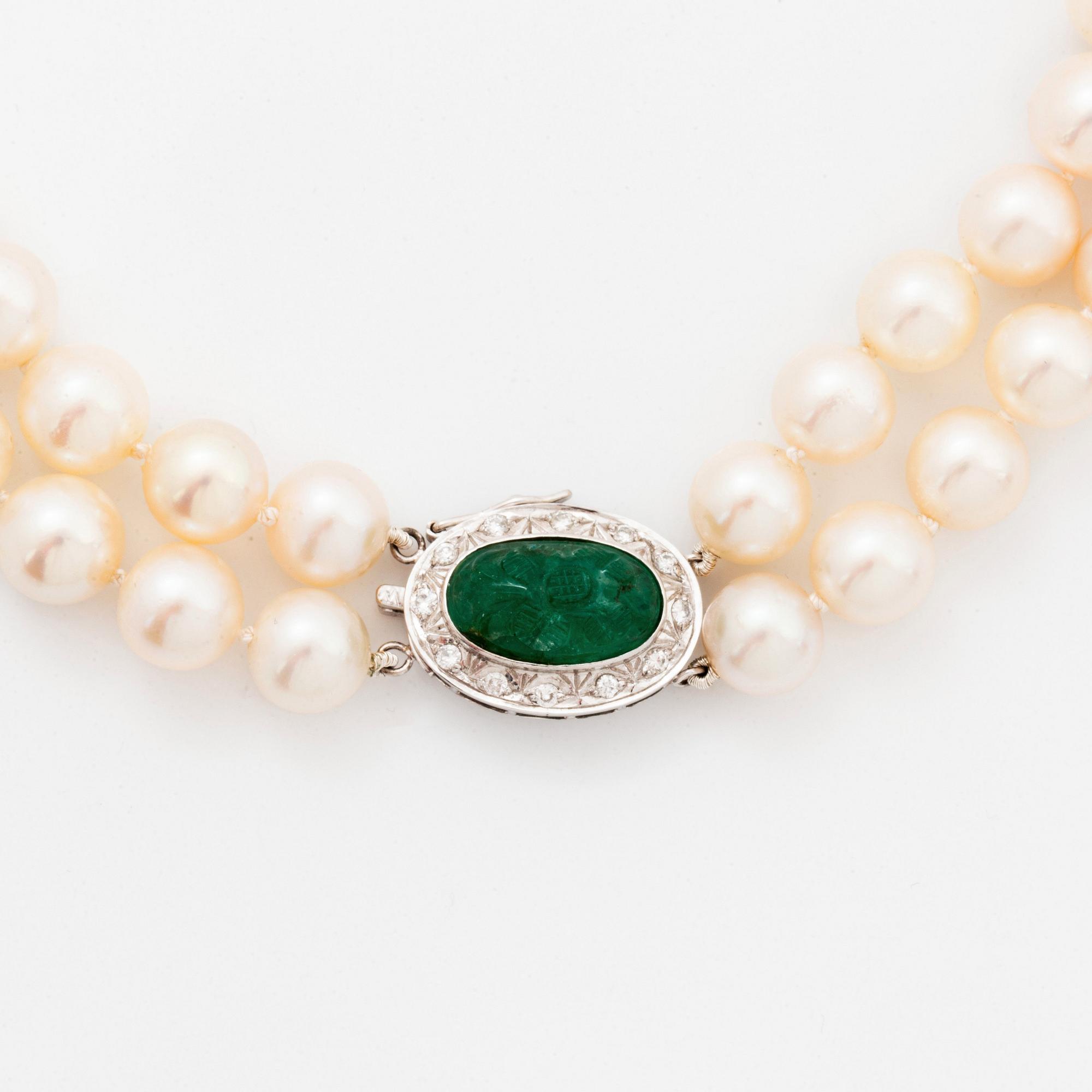 A two strand cultured pearl necklace with an 18K white gold and emerald clasp.