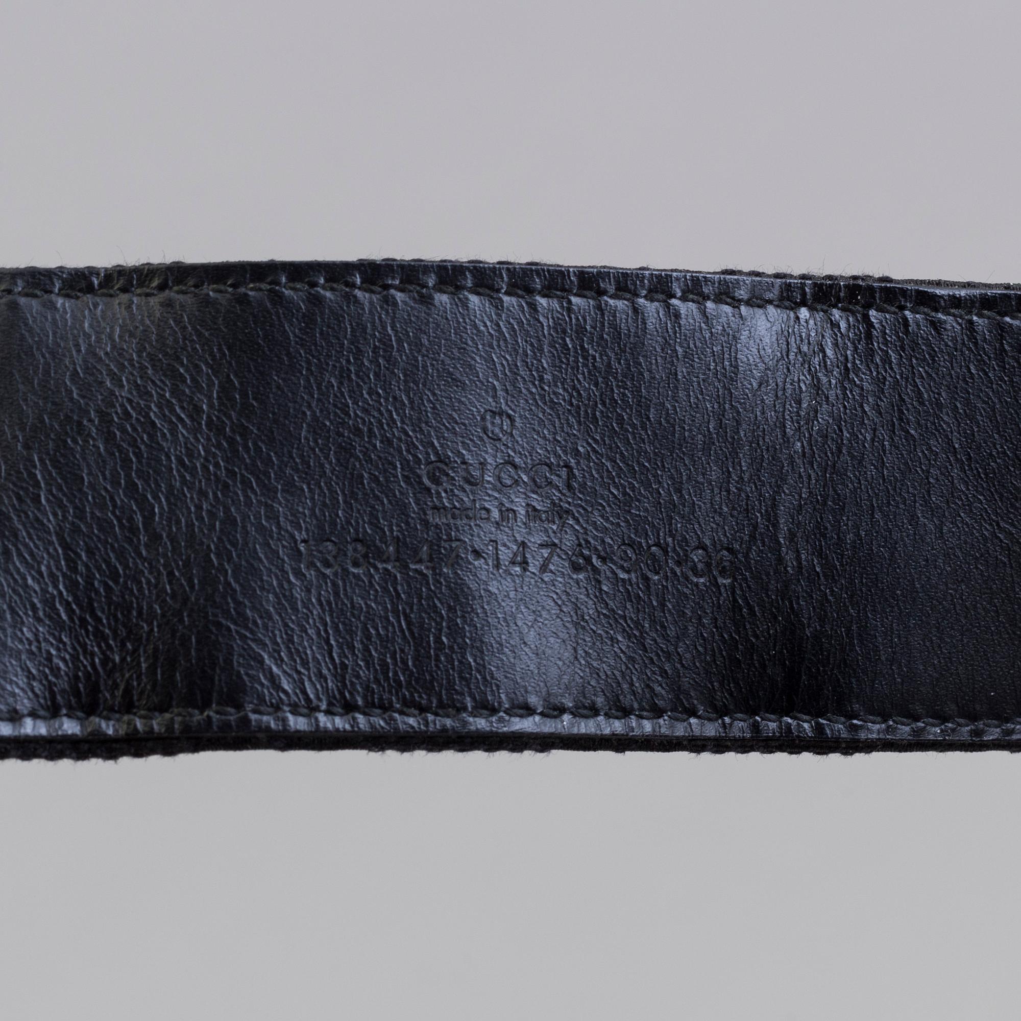 A blach monogram belt by Gucci.