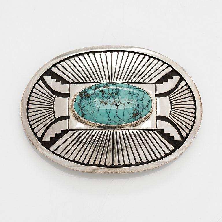Chester Benally, a silver belt buckle with a turquoise, Navajo.