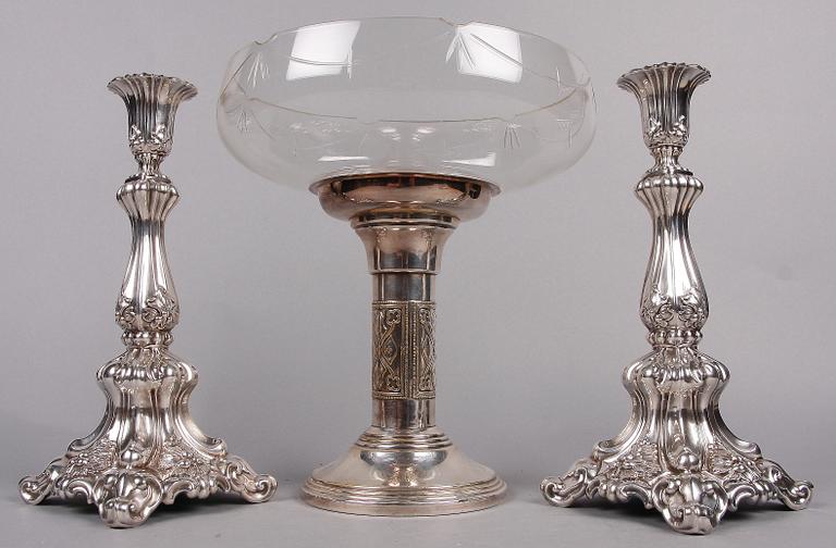 SKÅL PÅ FOT SAMT LJUSSTAKAR ett par, nysilver, 1900-talets första hälft.