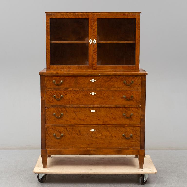 a chest of drawers with a vitrine cabinet from the early 20th century.