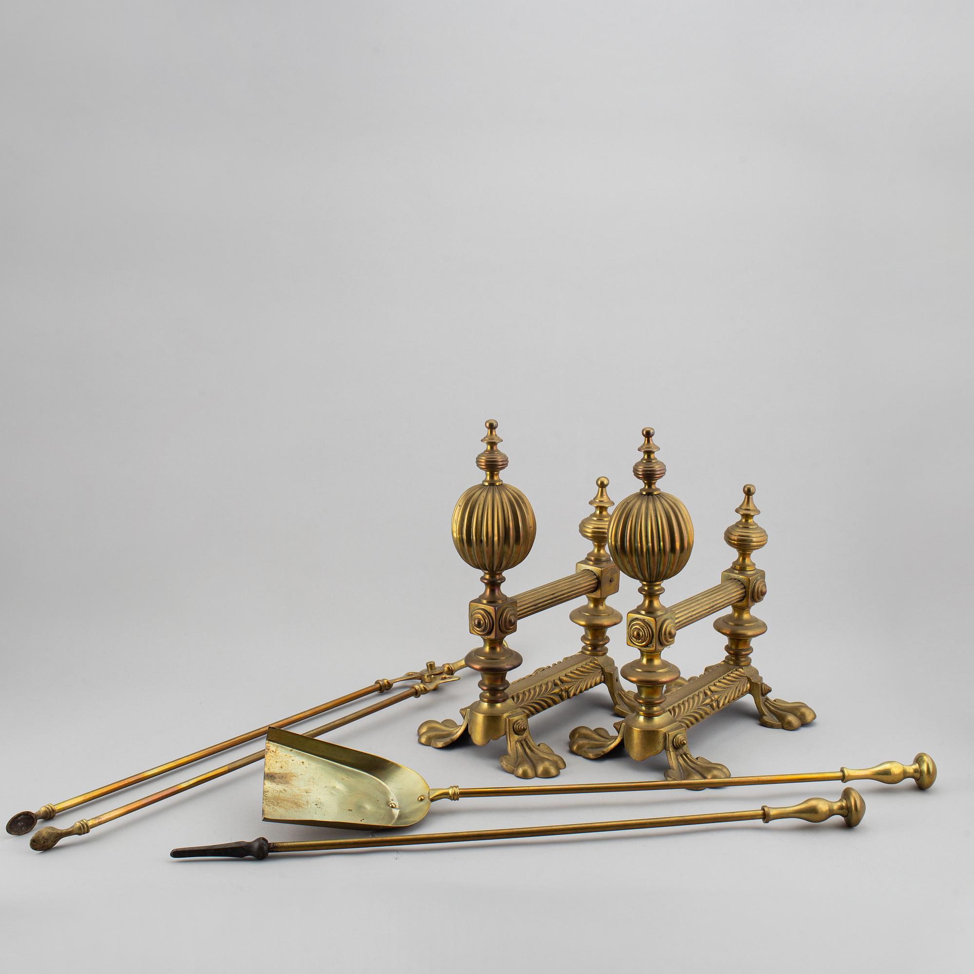 A pair of brass fire dogs and a brass fireplace poker set.