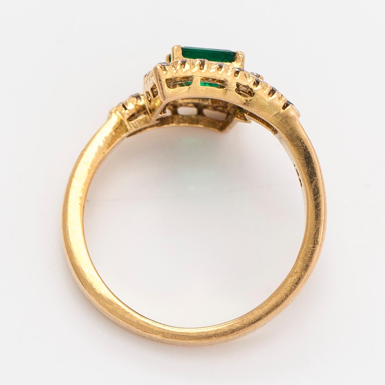 An 18K gold ring with emeralds and diamonds.
