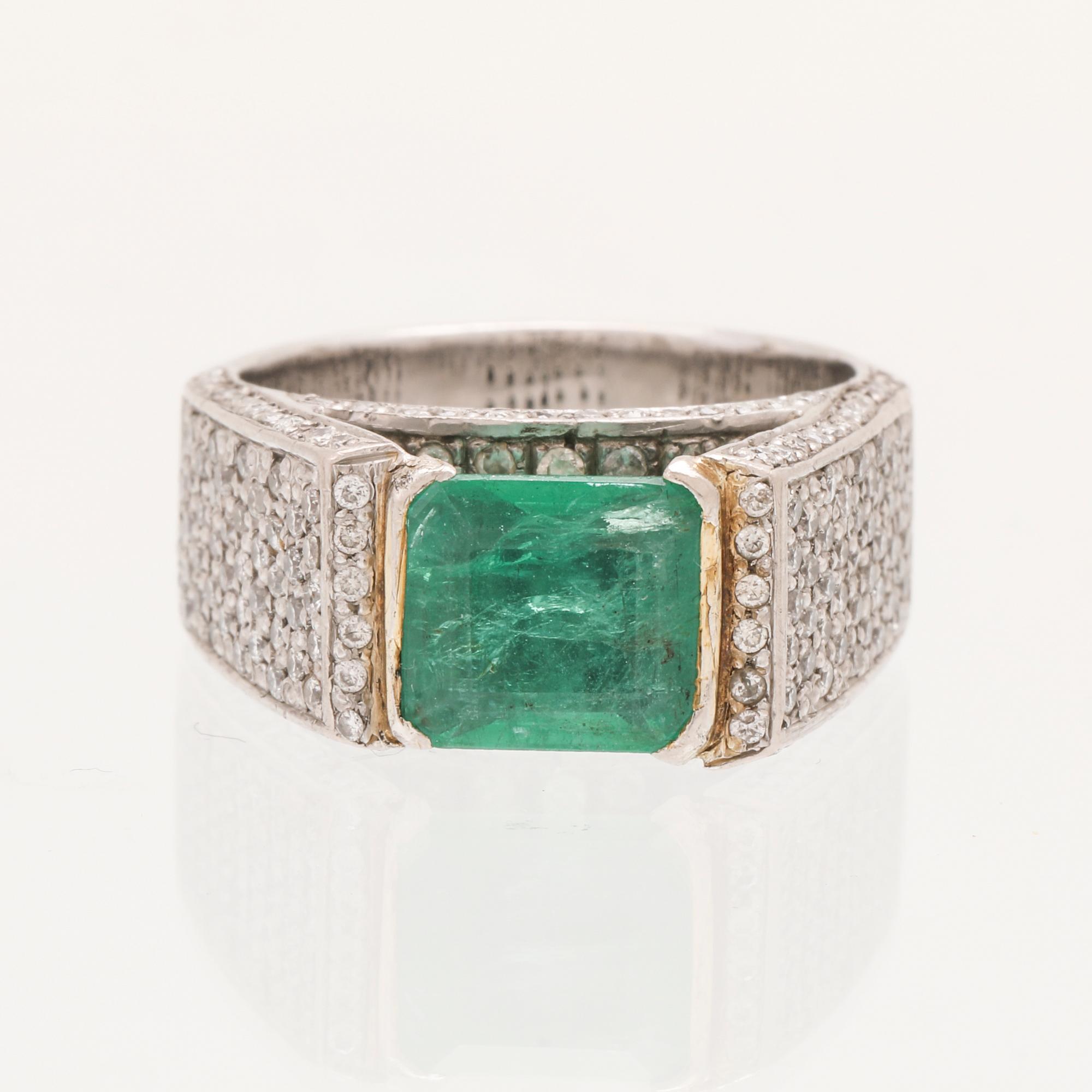A 9K white gold ring with an emerald and brilliant cut diamonds.