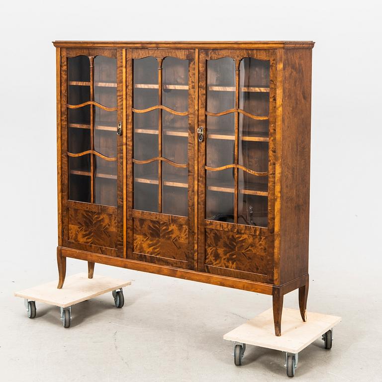 A glass and veneered cabinet from the first half of the 20th century.
