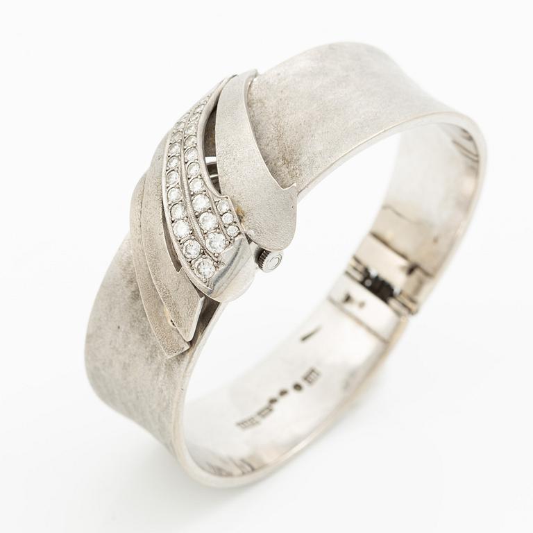 Aftonklocka/armring, Bo Dolk, 18K vitguld med briljantslipade diamanter, 1970-tal.