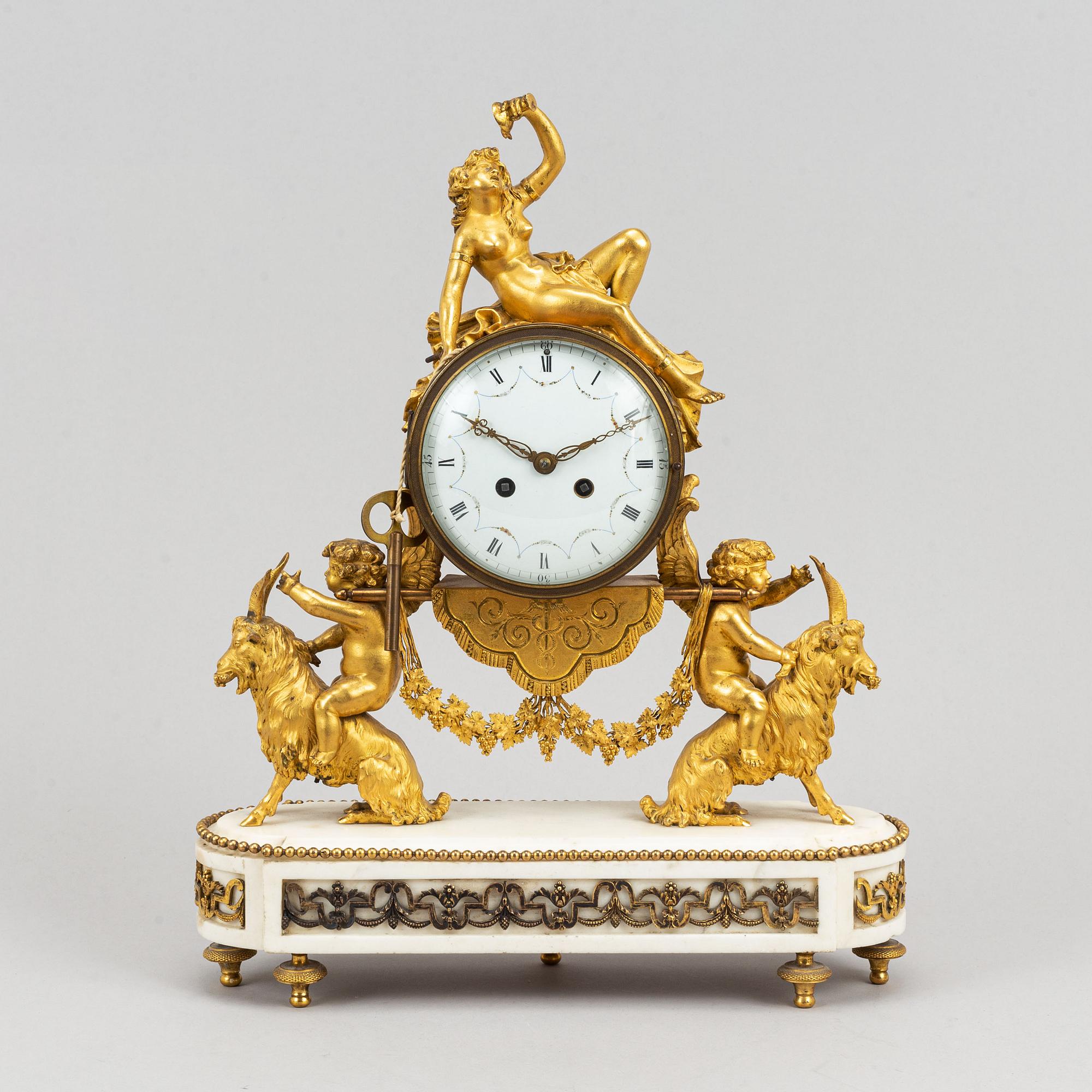 A marble and gilt bronze mantle clock in Louis XVI style, decorated with grapes, putti and a bacchant, 19th century.