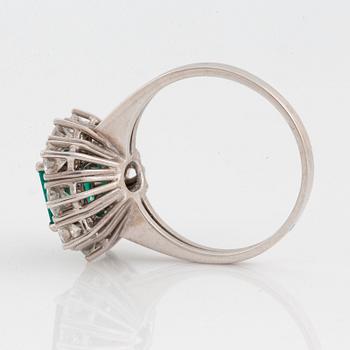 An 18K white gold ring set with a faceted emerald ca 1.15 cts and round brilliant-cut diamonds.