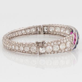 A platinum bangle set with old- and rose-cut diamonds and faceted sapphires and rubies.