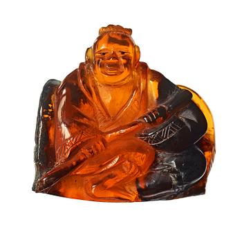 132. An amber figurine of a sitting man with baskets, Qing dynasty (1644-1912).