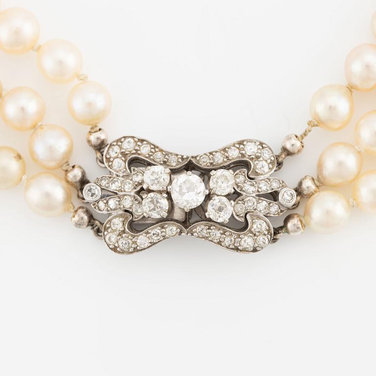 A three-strand cultured pearl necklace with an 18K white gold clasp with round brilliant-cut diamonds.