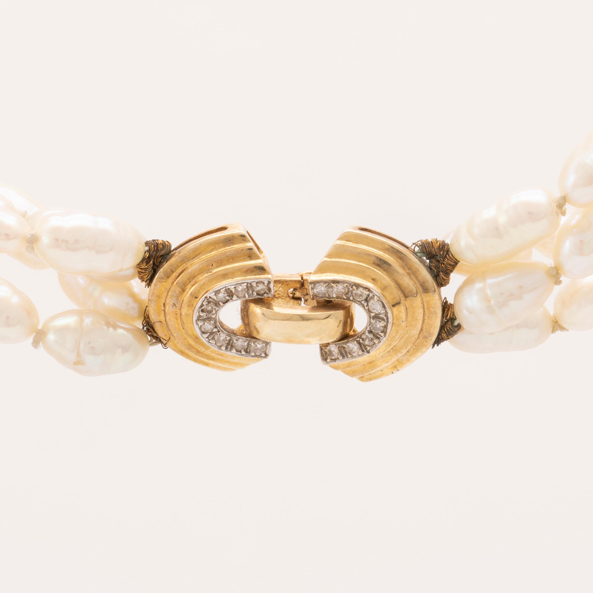 A necklace of cultured pearls set with a 14K gold lock and round brilliant cut diamonds.