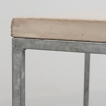 A modern sofa table with concrete top and steel legs.
