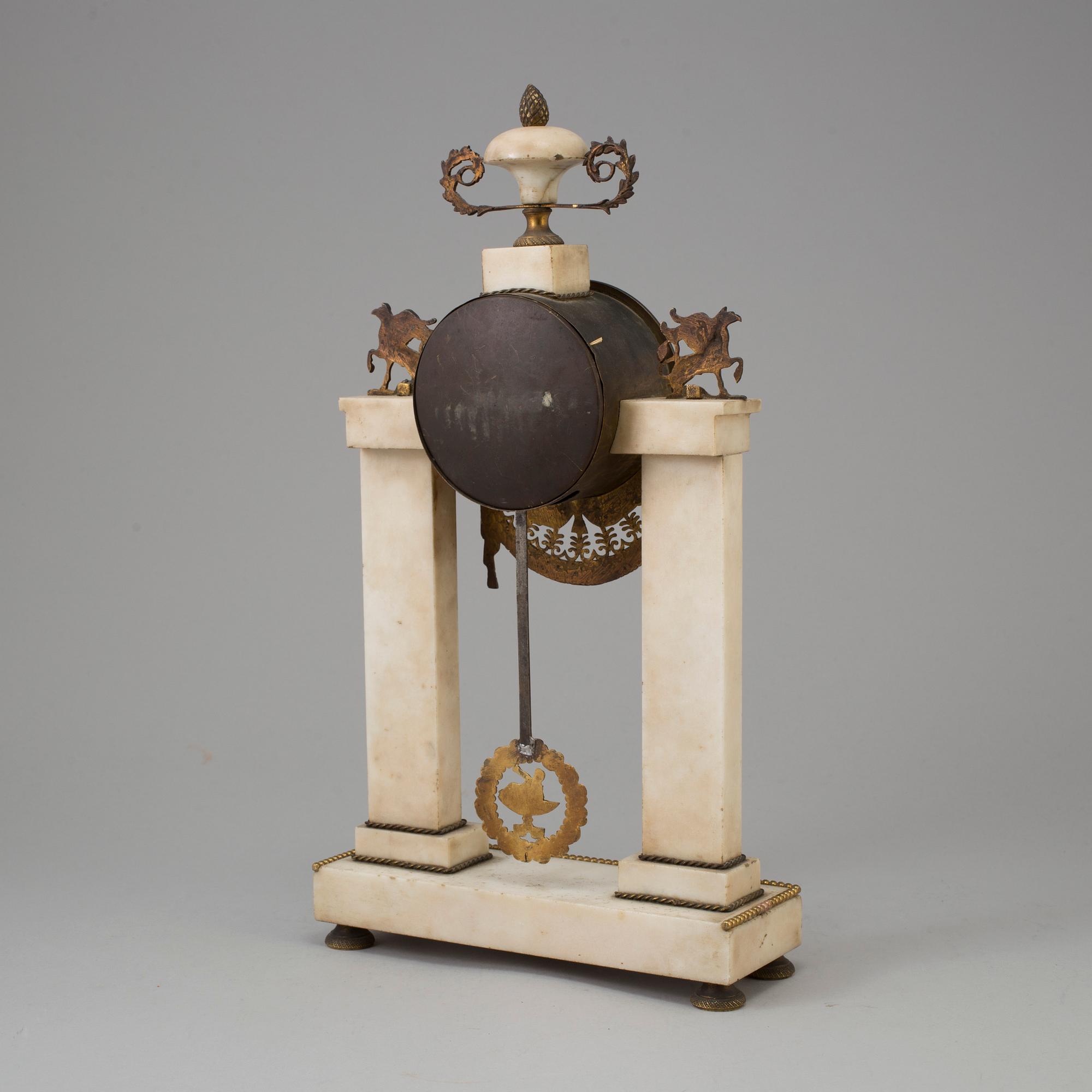A FRENCH EMPIRE MARBLE AND BRASS MANTEL CLOCK, first half of the 19th century.