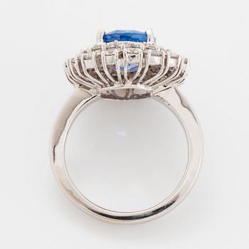 An 18K white gold ring set with an oval faceted sapphire and round brilliant-cut diamonds.