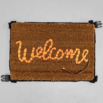 Banksy, "Welcome", Hand-stitched doormat using the fabric from life vests, 2019.