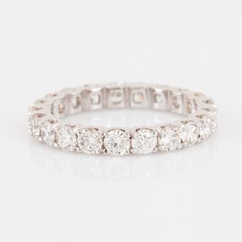 An 18K gold eternity ring set with round brilliant-cut diamonds.