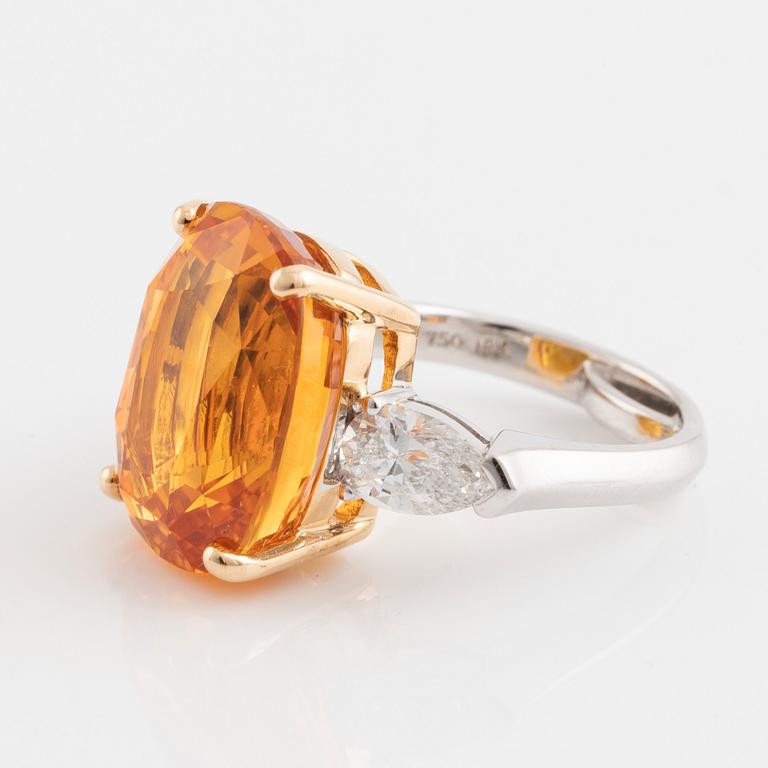 An 18K white gold ring set with a cushion shaped orange-yellow sapphire.