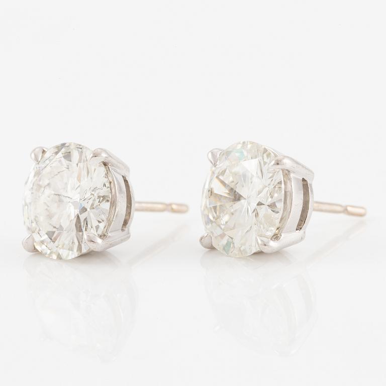 A pair of earrings in 18K white gold set with two round brilliant-cut diamonds.