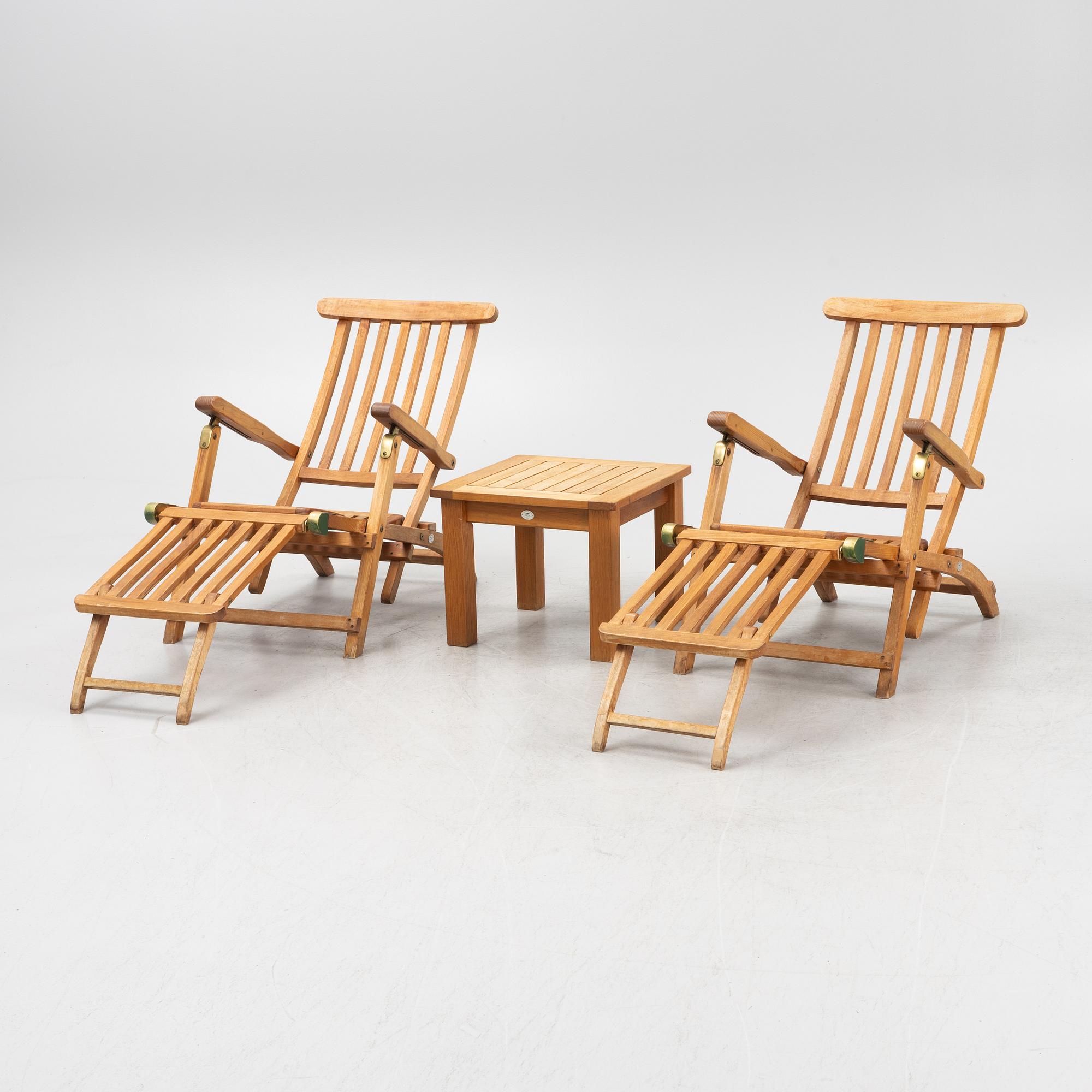 A pair of teak deck chairs and a table, 21st Century.