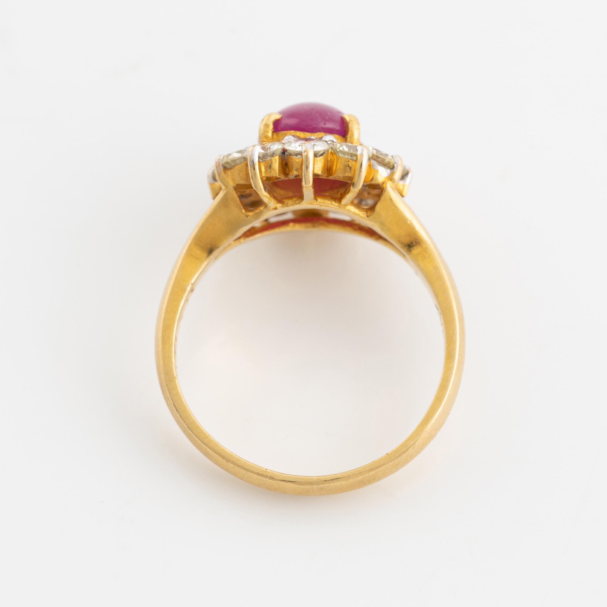 An 18K gold ring set with a cabochon-cut ruby and round brilliant-cut diamonds.