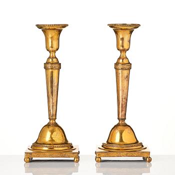 A pair of late George III gilt-copper candlesticks, early 19th century.
