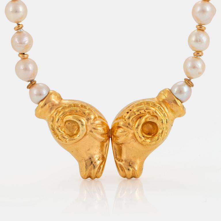 An 18K gold pendant with a cultured pearl necklace.