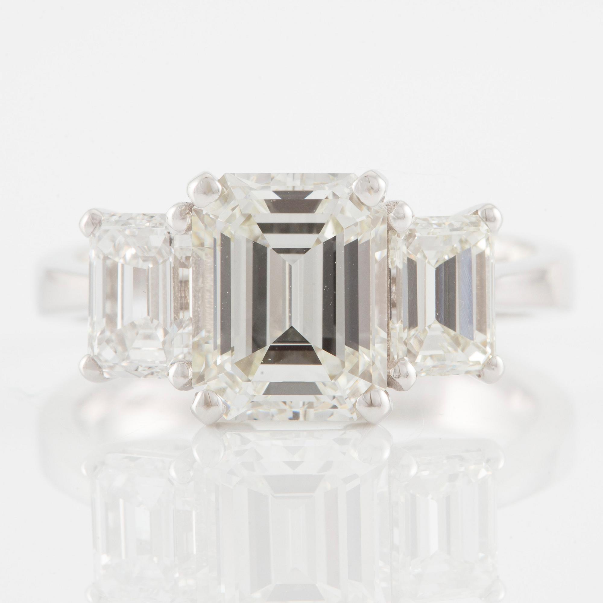 An 18K white gold ring set with three emerald-cut diamonds.