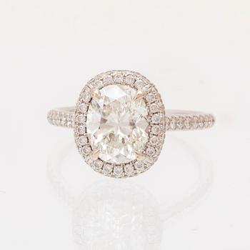 An 18K white gold ring by James Allen, set with an oval brilliant cut diamond in a halo of round brilliant cut diamonds.