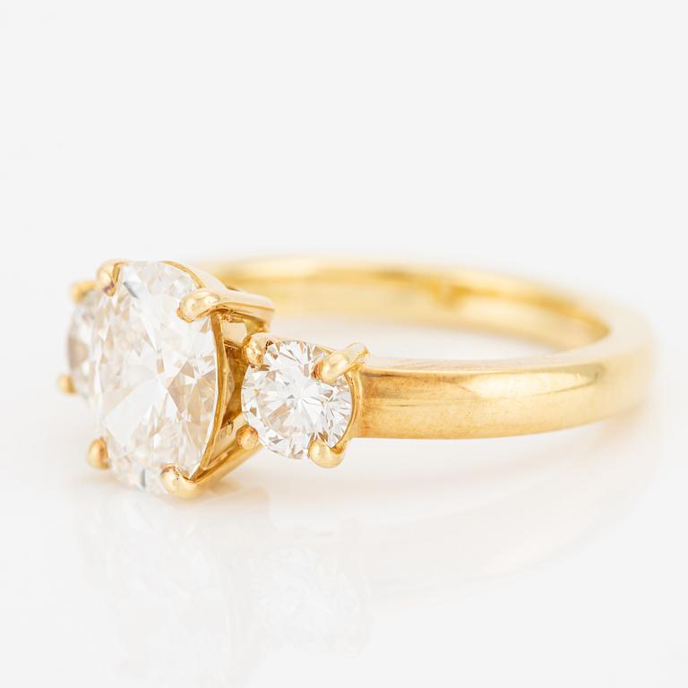 A ring in 18K gold with an oval brilliant-cut diamond and two round brilliant-cut diamonds.