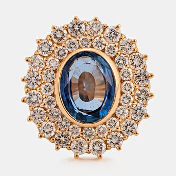 1013. An 18K gold ring set with a faceted sapphire ca 3.50 cts and round brilliant-cut diamonds.