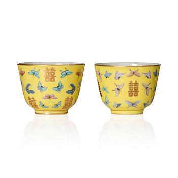 1095. A pair of yellow glazed double happiness cups with butterflies, Qing dynasty, with Tongzhis four character mark to base.