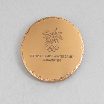 Deltagarmedalj OS Nagano 1998 samt ett tygmärke för den Svenska OS-truppen.
