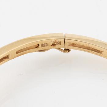 A bangle in 14K gold with round brilliant-cut diamonds.