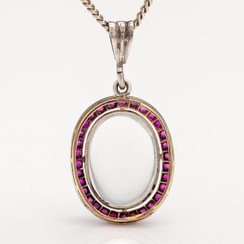 A 14K gold and silver necklace with a moon stone, rubies and a red glass stone.