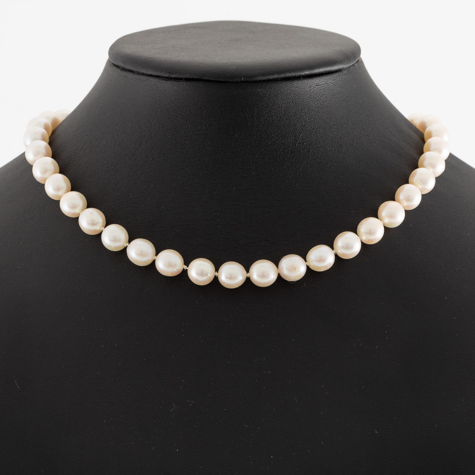 Pearl necklace, cultured pearls with a clasp in 18K white gold set with emeralds, diamonds, and pearls.