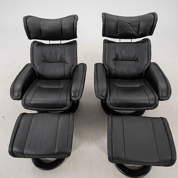 A pair of leather easy chairs and footstools from the 21st century.
