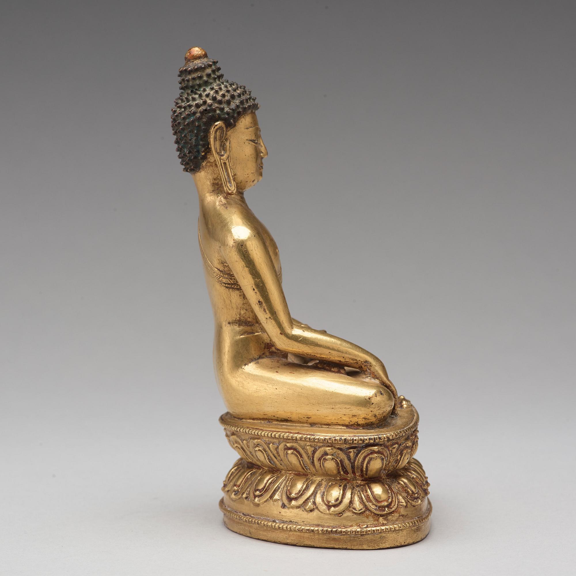 A gilt copper alloy figure of Akshobhya, Tibet, 16th Century.