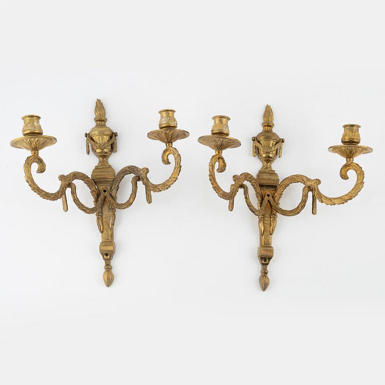 A pair of brass Louis XVI-style two-light wall lights, early 20th Century.