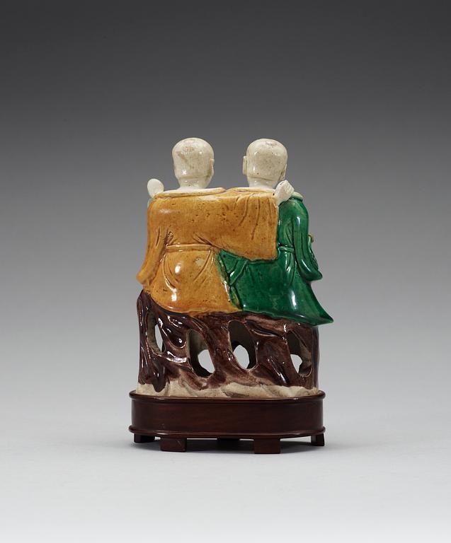 A green, yellow and brown glazed biscuit figure of Laughing boys, Qing dynasty, Kangxi (1662-1722).