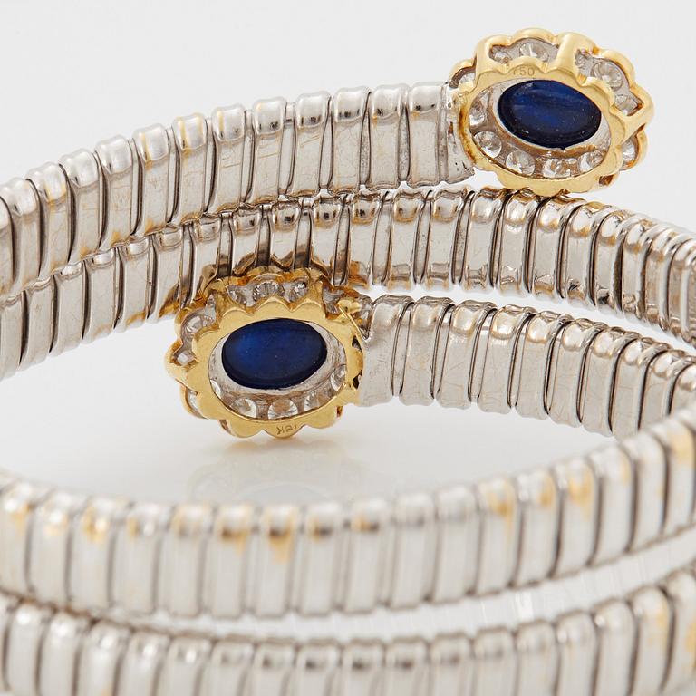 An 18K gold bangle set with cabochon-cut sapphires and round brilliant-cut diamonds.