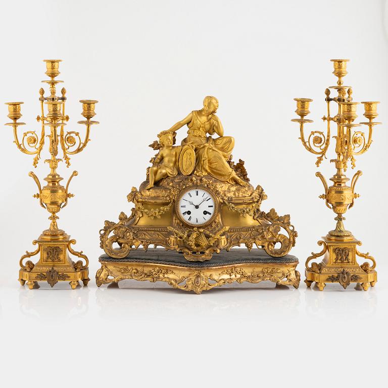 A table clock and a pair of candelabras, Louis XVI-style, France, beginning of the 20th century.