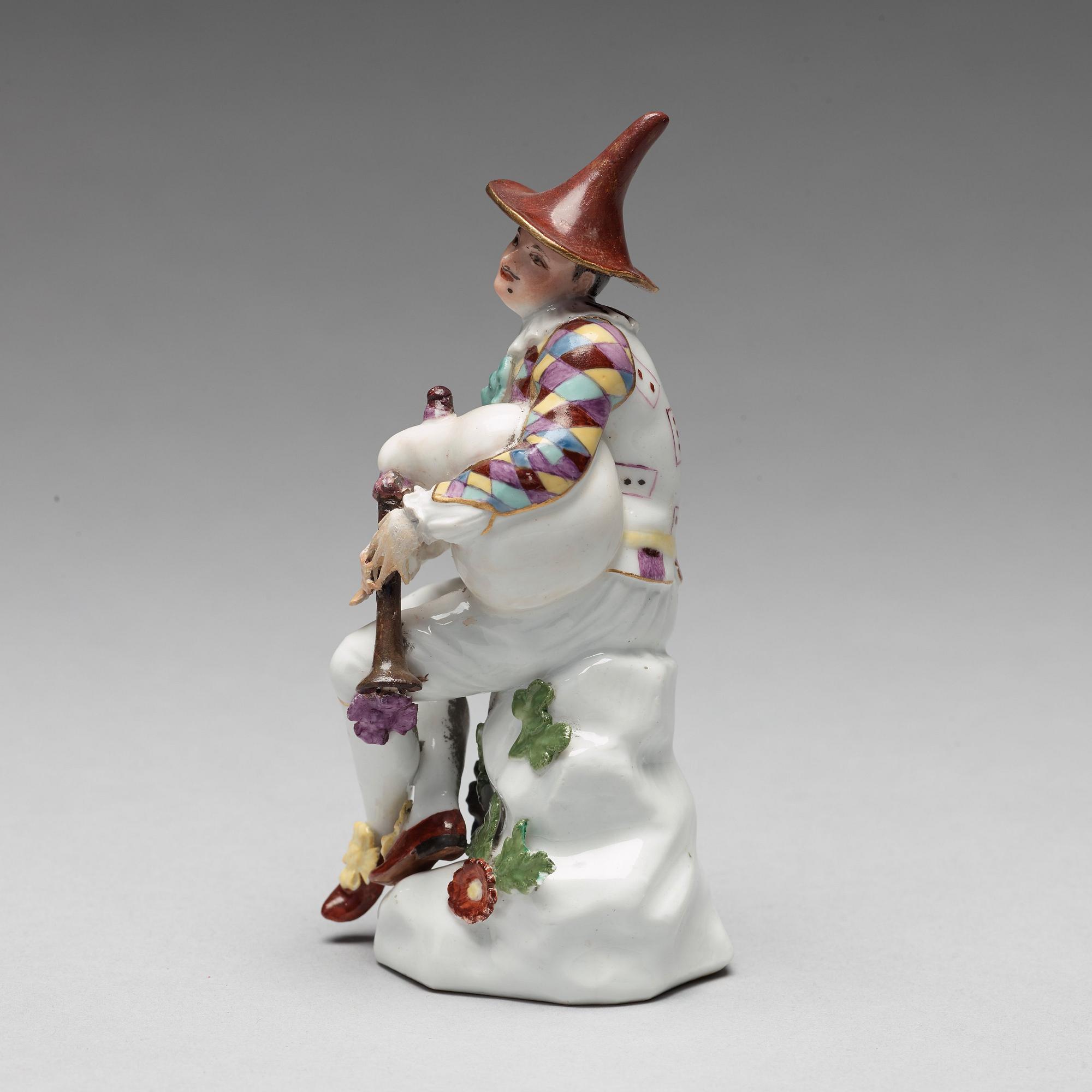 A porcelain figure of harlekin playing the bagpipe, circa 1900.