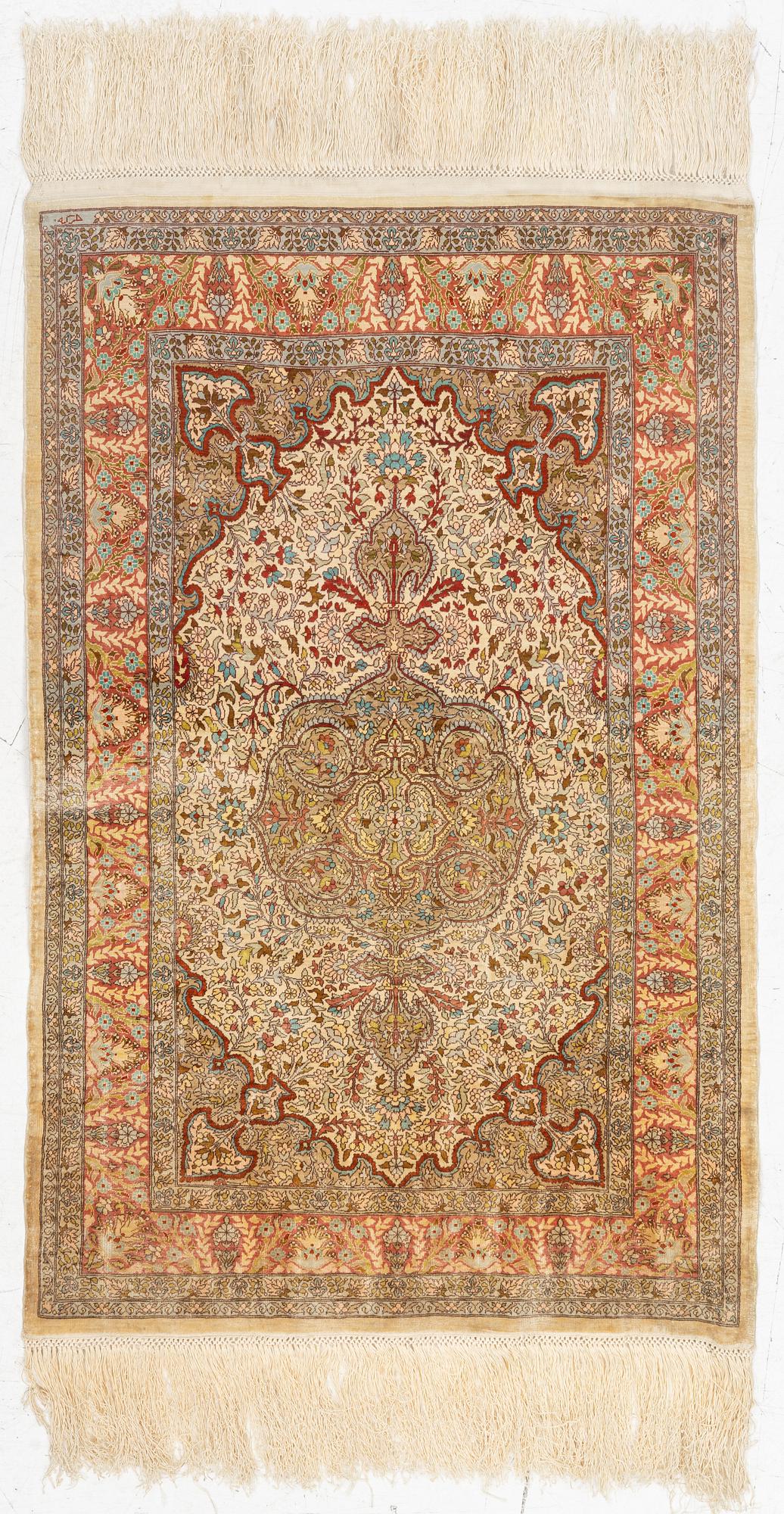 A silk Hereke rug, c. 85 x 55 cm.