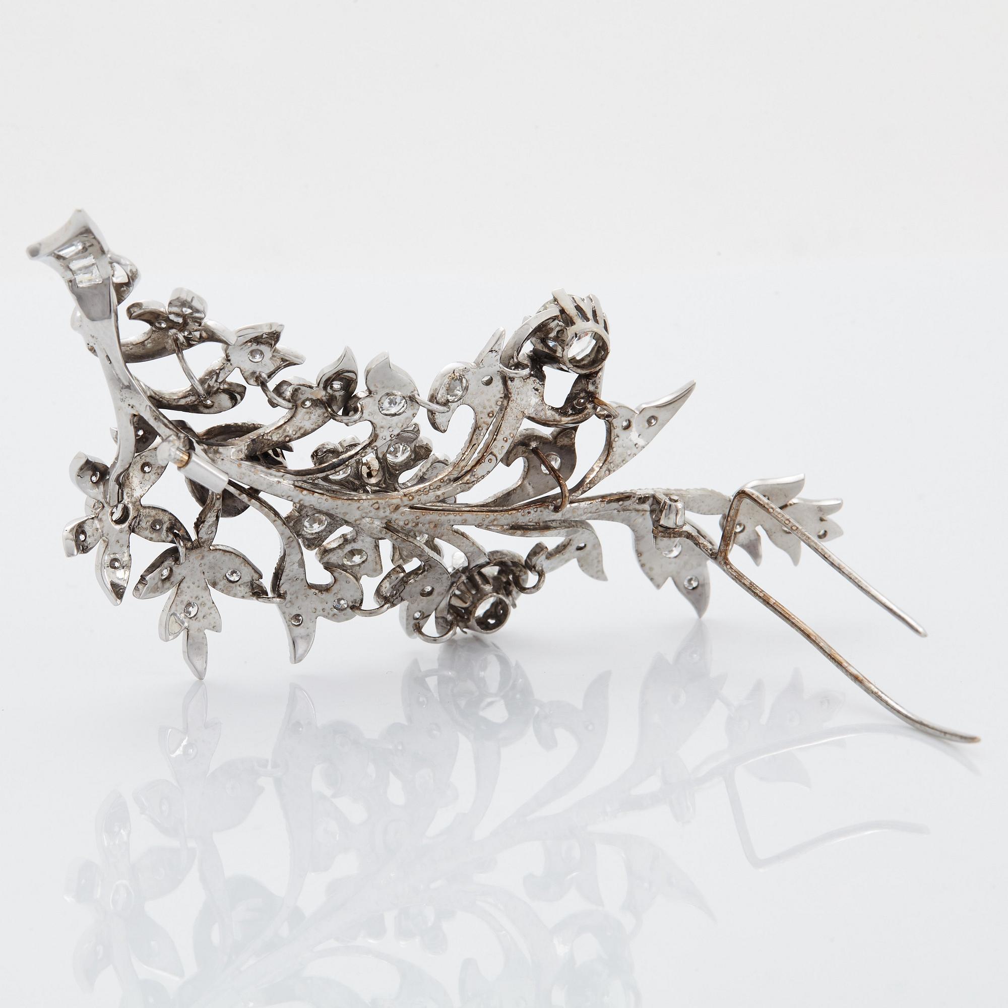 An 18K white gold brooch set with round brilliant-cut diamonds.
