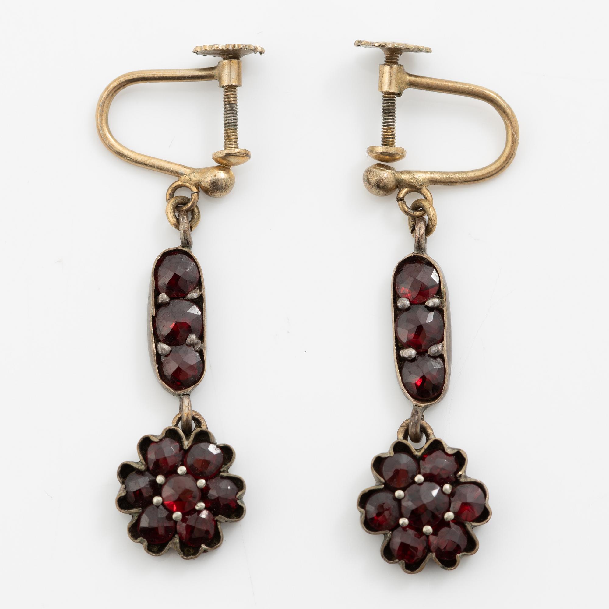 Garniture, necklace/bracelet and earrings in silver with garnets in the form of floral motifs, around the turn of the 20th century.