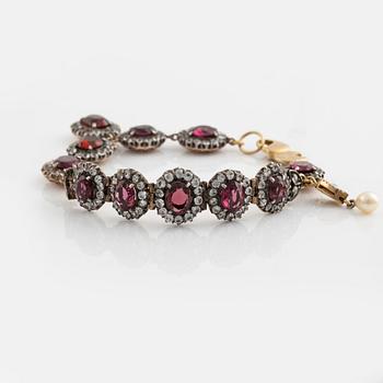 Bracelet with garnets and white stones, two charms, one eye enamel with brilliant cut diamonds, possibly oriental pearl.