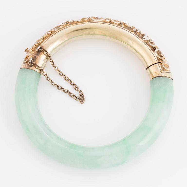 A jade bangle with a gilded silver clasp.