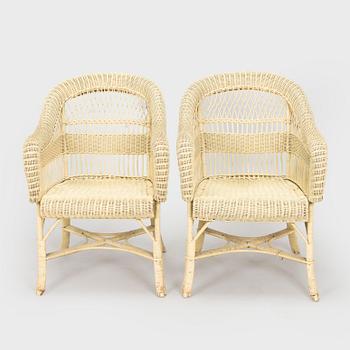A mid-20th-century three-piece rattan furniture set including two armchairs, and a table.